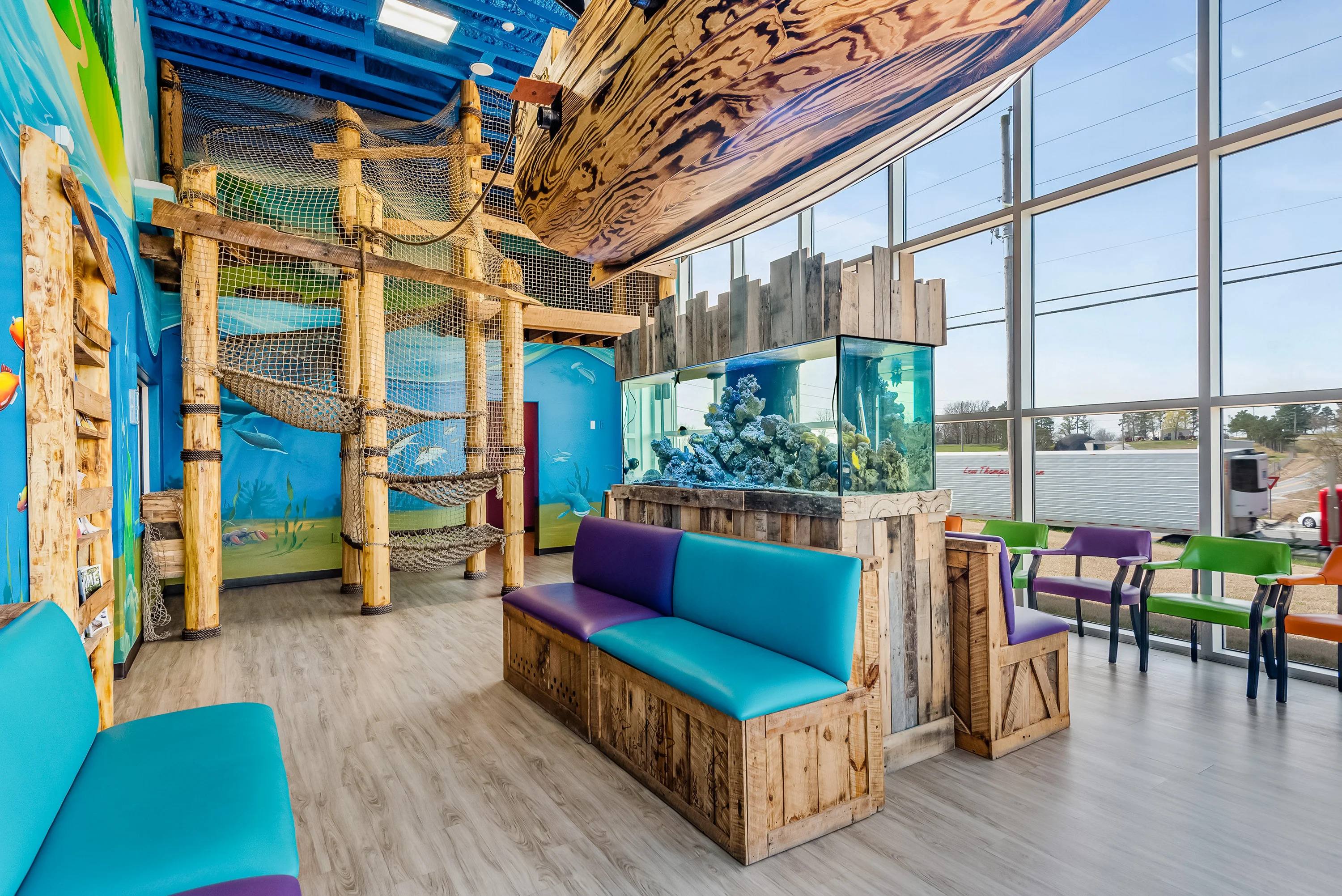 The Super Smiles waiting room, a 30-foot pirate ship hangs over a fish tank, with a rope-gym hideout above and aqua bench seating below