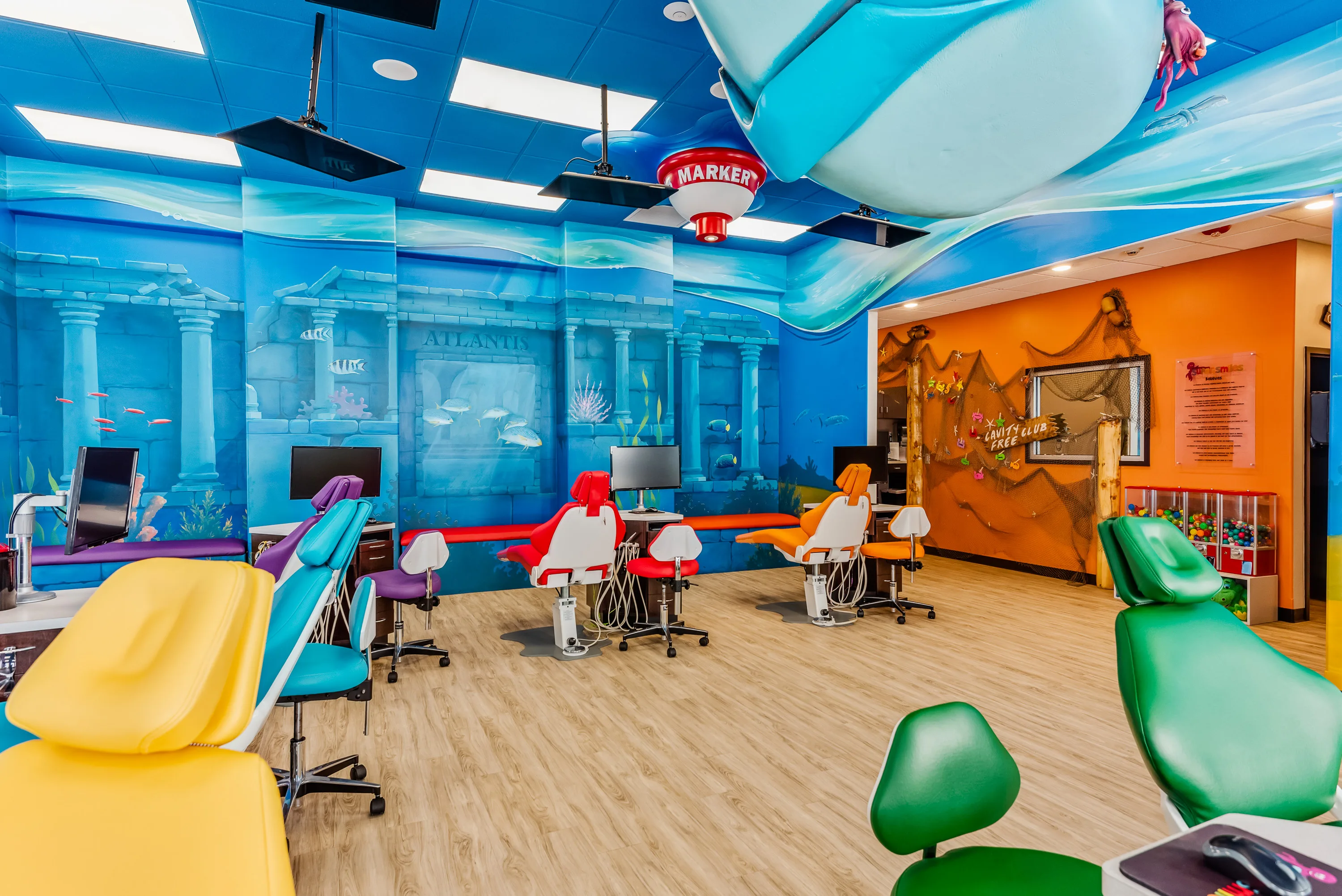 A Super Smiles treatment room with an undersea mural and the Cavity Free Club wall visible through the doorway